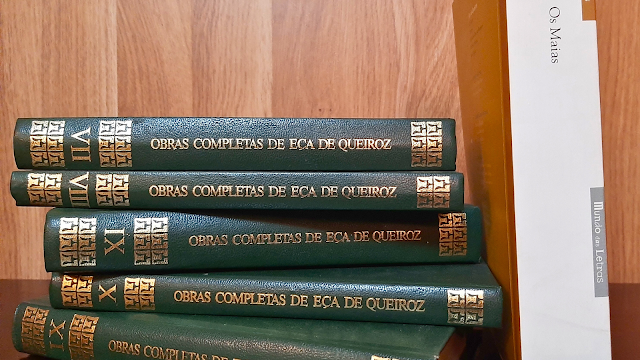 Eça de Queiroz: o olhar crítico da literatura portuguesa Coleção de volumes encadernados das Obras Completas de Eça de Queiroz empilhados sobre uma mesa, ao lado do livro Os Maias — fotografia ilustrando artigo sobre o autor português.