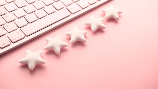 A ilusão de sermos melhores que a média Teclado branco sobre fundo rosa com estrelas alinhadas, simbolizando avaliações e a perceção de sermos melhores que a média