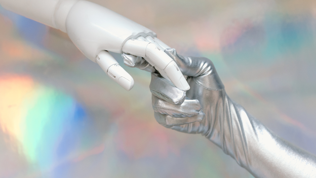 Mão robótica a tocar numa mão humana com luva prateada, simbolizando a ligação entre tecnologia e energia futurista.