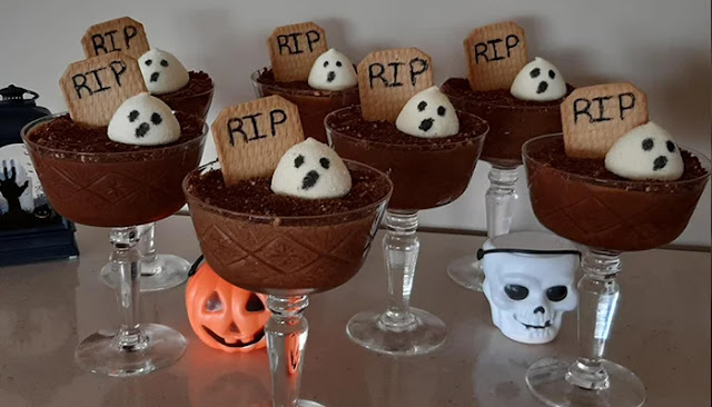 Mousse de chocolate assustadora para o Halloween Taças de mousse de chocolate decoradas para o Halloween com bolacha “RIP” e marshmallows em forma de fantasmas.