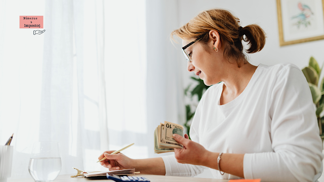 Como Organizar as Finanças Para o IRS 2026 Mulher a organizar as finanças em casa, contando dinheiro e anotando despesas numa mesa de trabalho, representando preparação e organização para o IRS 2026 em Portugal.