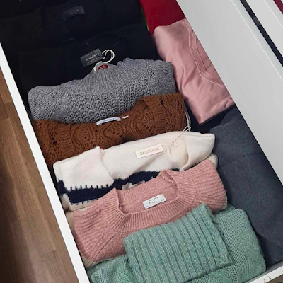 Gavetas de outono: camisolas organizadas ao pormenor Gaveta de closet com camisolas de outono enroladas e organizadas por cores, mostrando um método de arrumação que permite ver todas as peças facilmente.