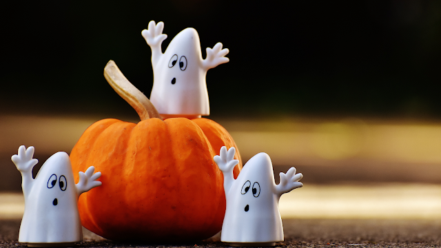 🎃 Fantasmas e abóbora: decoração de Halloween divertida Fantasmas decorativos ao lado de uma abóbora laranja, ideia criativa de decoração para o Halloween.