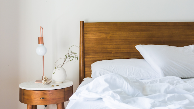 Cama com edredão macio e almofadas confortáveis, representando o conceito de bed rotting e descanso consciente.