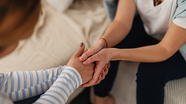 Apoio emocional no fim de uma relação Duas pessoas a segurar nas mãos, oferecendo apoio emocional durante o fim de uma relação