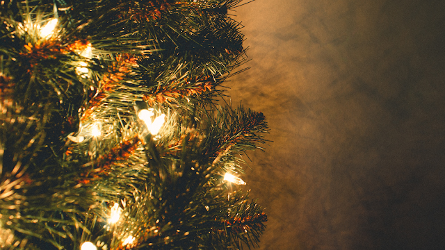 Luzes de Natal a iluminar ramos de pinheiro Ramos de árvore de Natal decorados com pequenas luzes douradas, criando um ambiente quente e acolhedor.