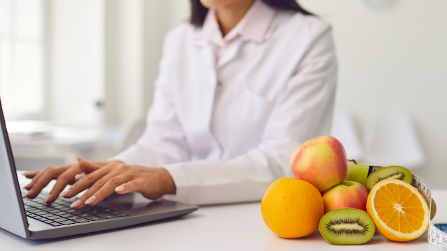 Profissional a trabalhar no computador com frutas frescas ao lado, simbolizando escolhas saudáveis e autenticidade