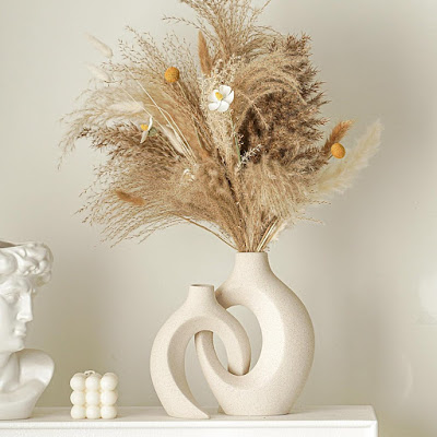 Jarras escultóricas com flores secas em decoração primaveril Jarras escultóricas em cerâmica clara com arranjo de flores secas e gramíneas naturais, criando uma decoração primaveril minimalista, elegante e inspirada na natureza.