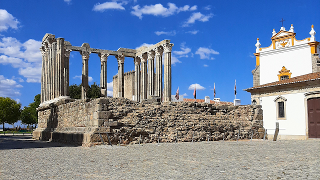 Templo Romano de Diana em Évora, monumento histórico rodeado por edifícios antigos e céu azul, um dos principais pontos turísticos da cidade.