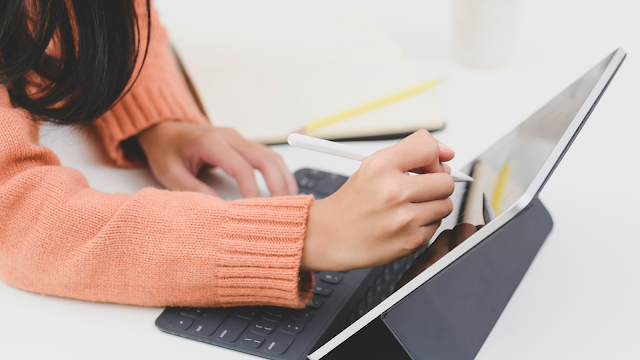 Mão de mulher escrevendo num computador, simbolizando produtividade e criatividade.