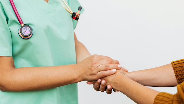 Empatia e cuidado no acompanhamento de doenças raras Profissional de saúde segura as mãos de uma pessoa, simbolizando empatia, apoio e acompanhamento no contexto das doenças raras.