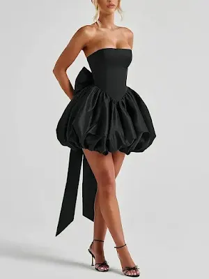 Elegant Black Strapless Bubble Hem Homecoming Dress with Bow Detail Model wearing a chic black strapless mini dress featuring a voluminous bubble skirt and a large bow on the back, paired with black strappy heels against a neutral background.
